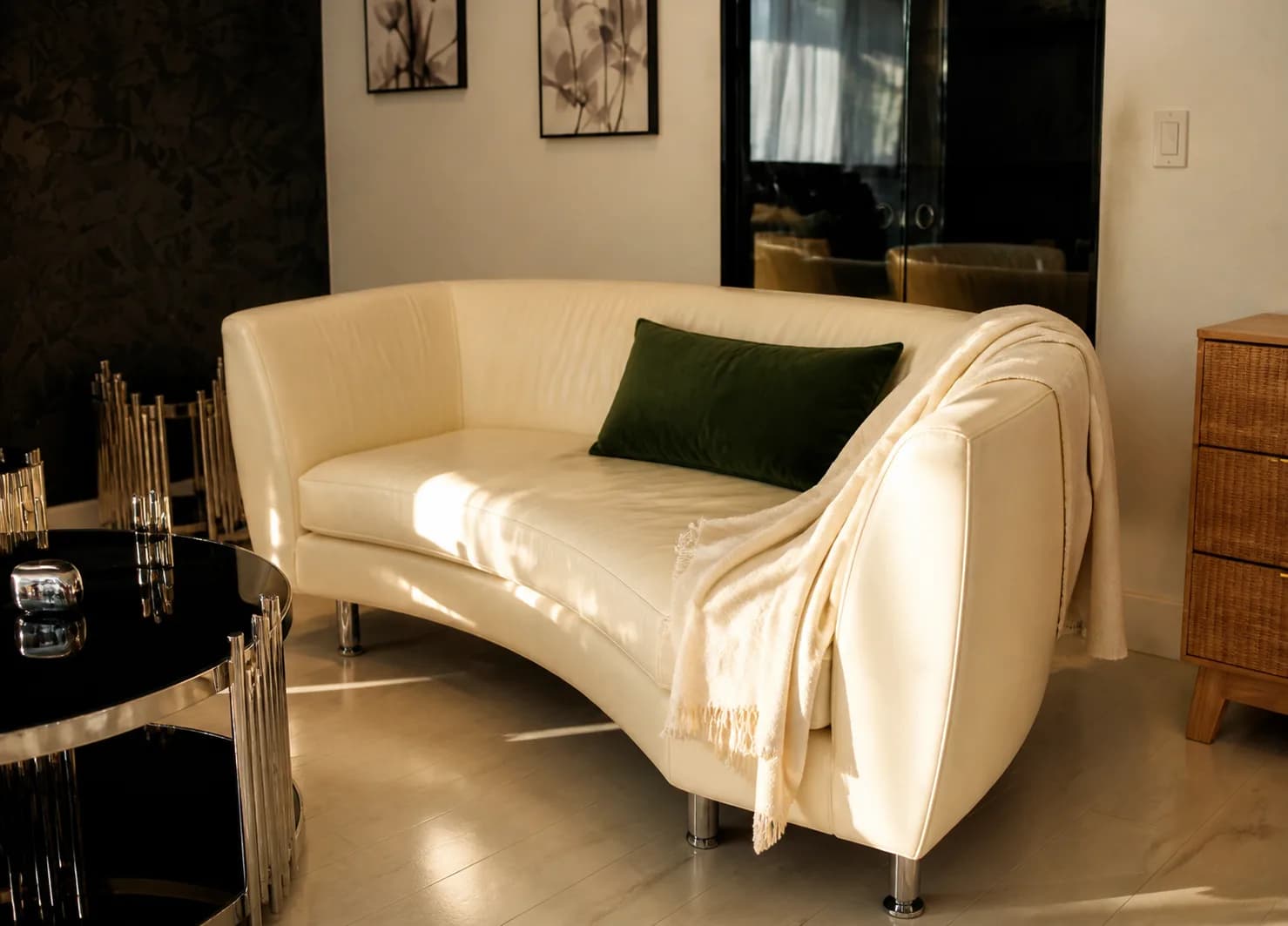 A white curved sofa with a green throw pillow in a quiet sitting room at Providence Detox.