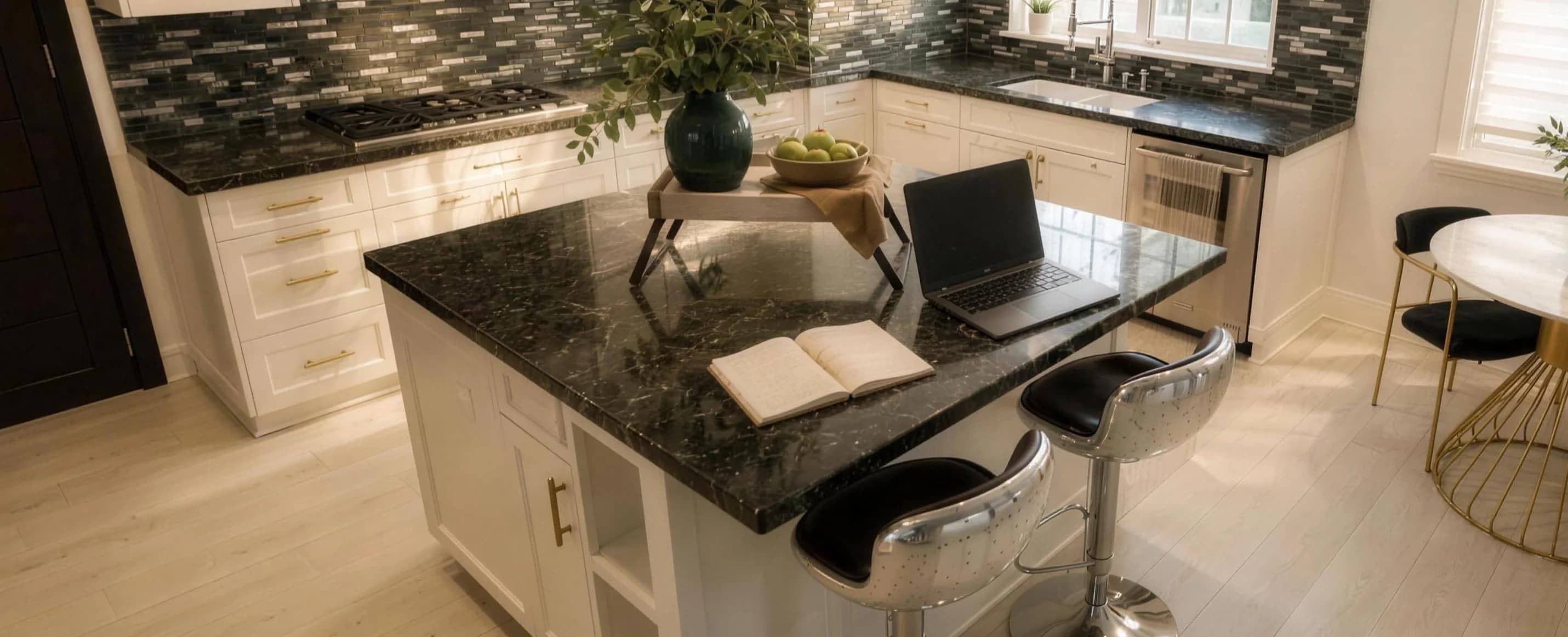 The kitchen island at Providence Detox, an open notebook and a laptop on dark granite, two stools drawn up to it.