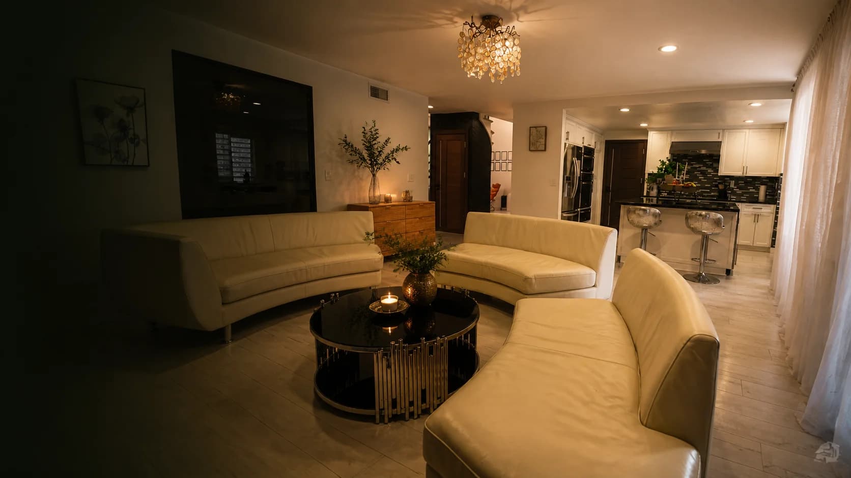Family lounge with curved cream sofas under a shell chandelier.