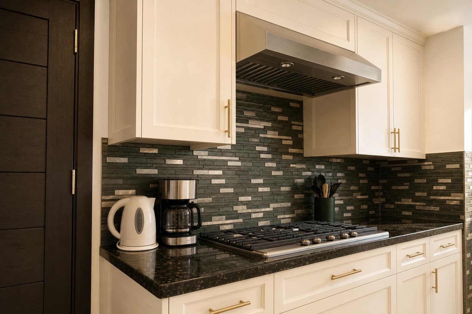 The residence kitchen, cream cabinets against a dark tile backsplash and black granite counter.